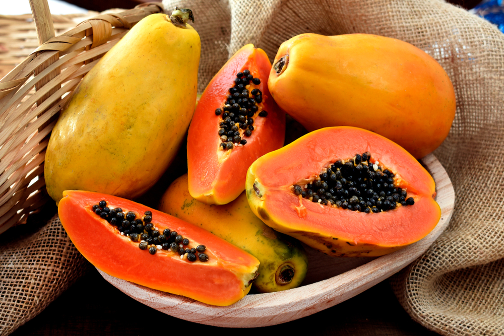 The papaya fruits in a wooden pot and a straw basket and rustic fabric at the background