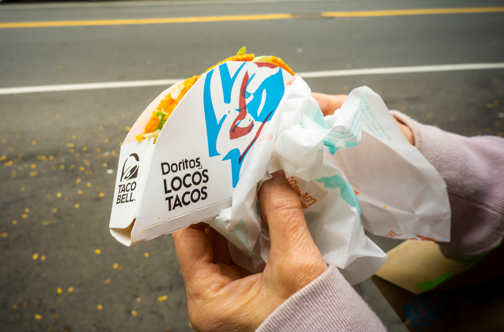 New York NY/USA-October 30, 2019 A consumer eats a Doritos Locos Taco outside of a Yum BrandsÕ Taco Bell franchise in the Greenwich Village neighborhood of New York