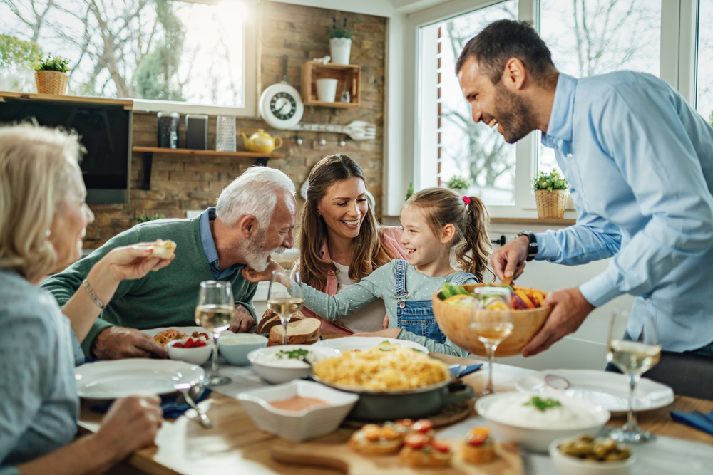 Happy multi-generation family gathering around dining table and having fun during a lunch.