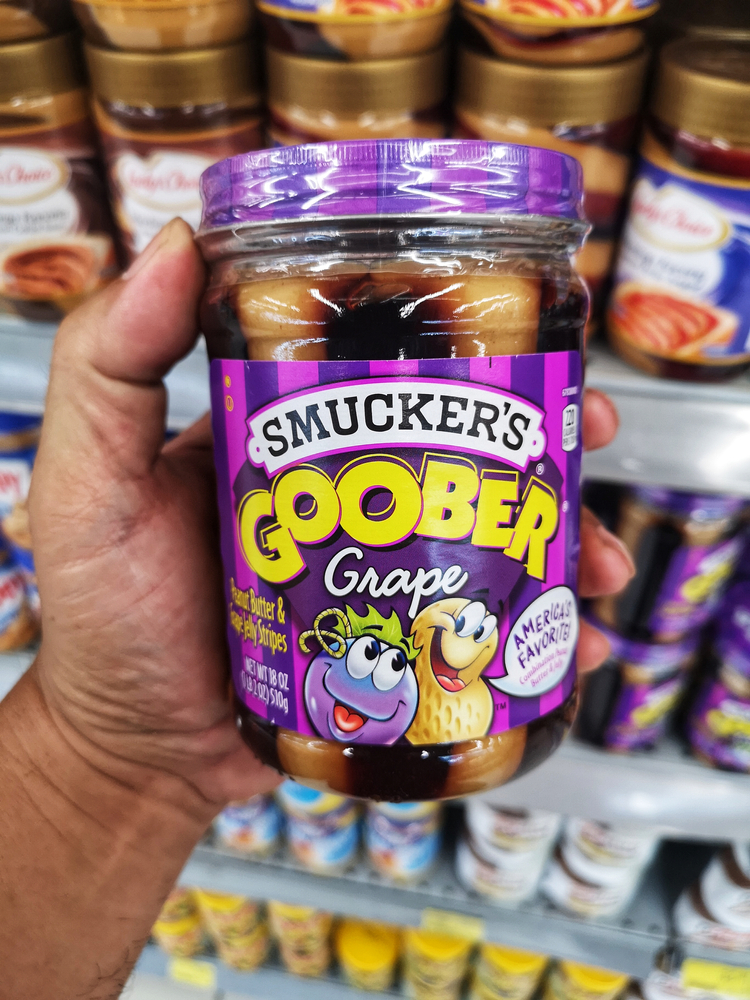 Klang, Malaysia - 10 July 2020 : Hand hold a jar of SMUCKER'S Goober Grape for sell in the supermarket with selective focus.