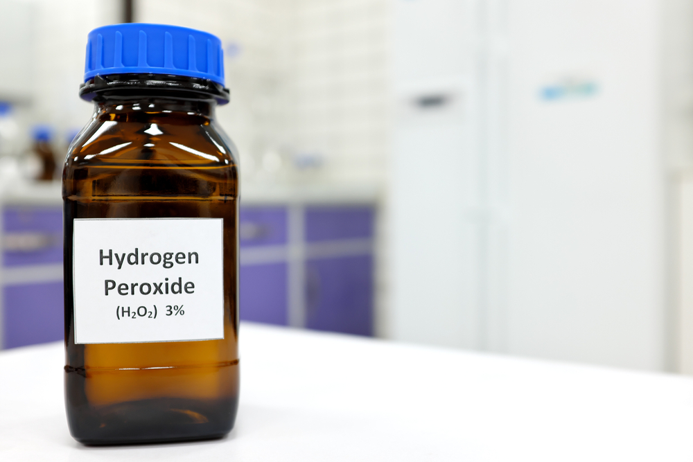 Selective focus of hydrogen peroxide solution in brown amber bottle. Blur laboratory background with copy space.