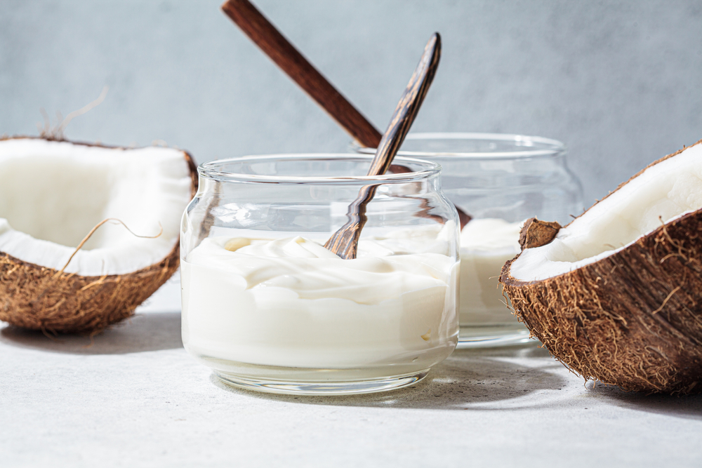 Vegan coconut yogurt in glass jars, white background.