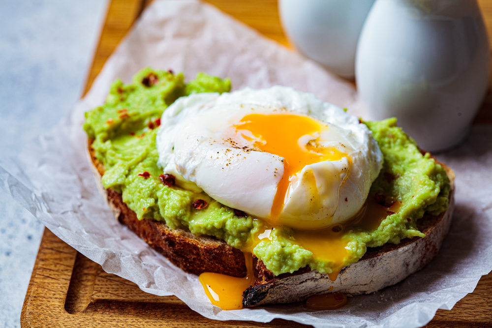 Avocado toast with poached egg on a wooden board. Breakfast concept.