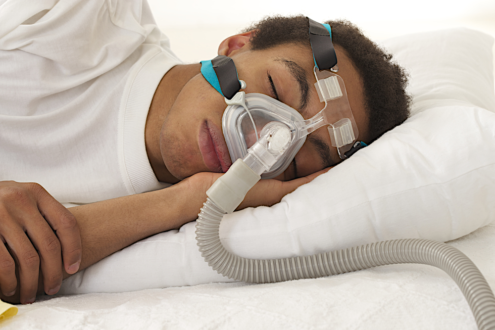 young man sleeping with apnea and CPAP machine