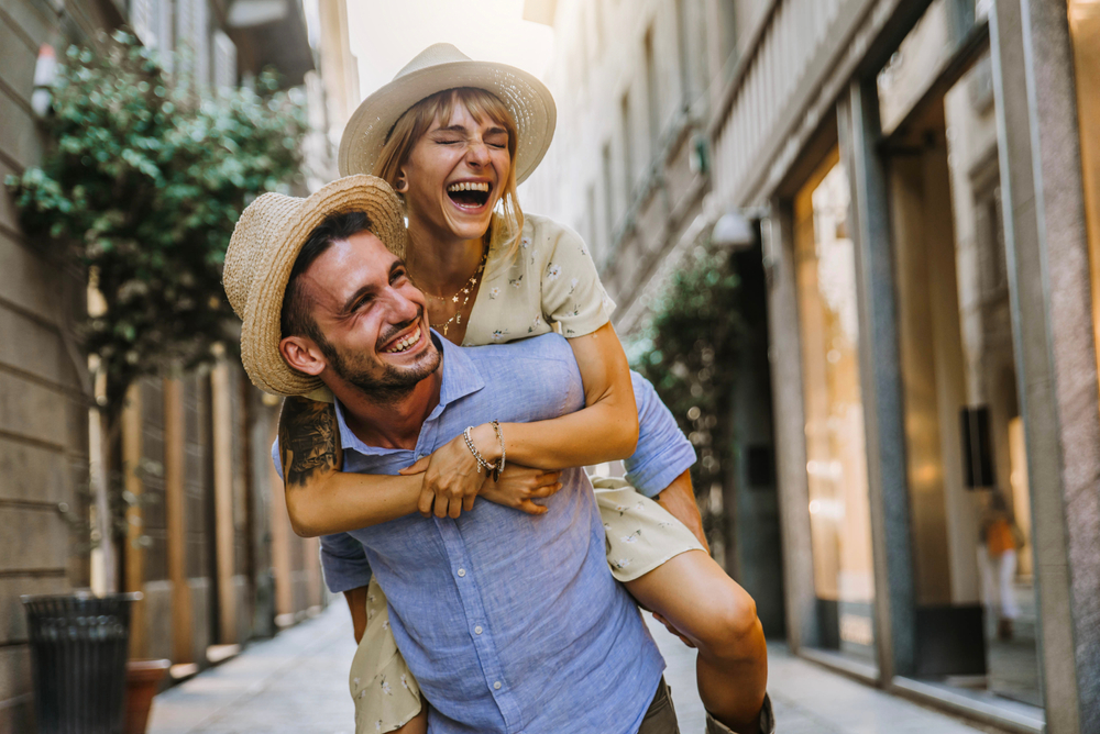 Couple of tourists having fun walking on city street at holiday - Happy friends laughing together on vacation - People and holidays concept