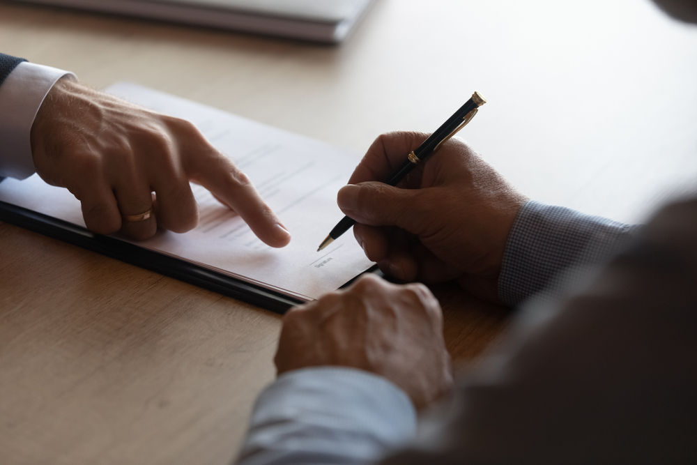 Hands of lawyer pointing at paper for businessman signing contract. Solicitor, legal advisor helping mature client to fill up document, medical insurance form, will, affixing signature. Paperwork
