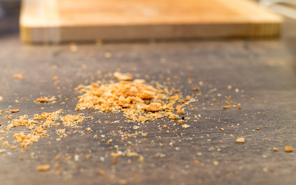 A small pile of breadcrumbs on the kitchen counter