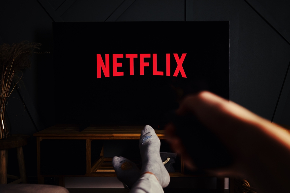 Online streaming service. Boy hold remote control in hand and TV set with NETFLIX service logo. Katy Wroclawskie, Poland - October 25, 2021
