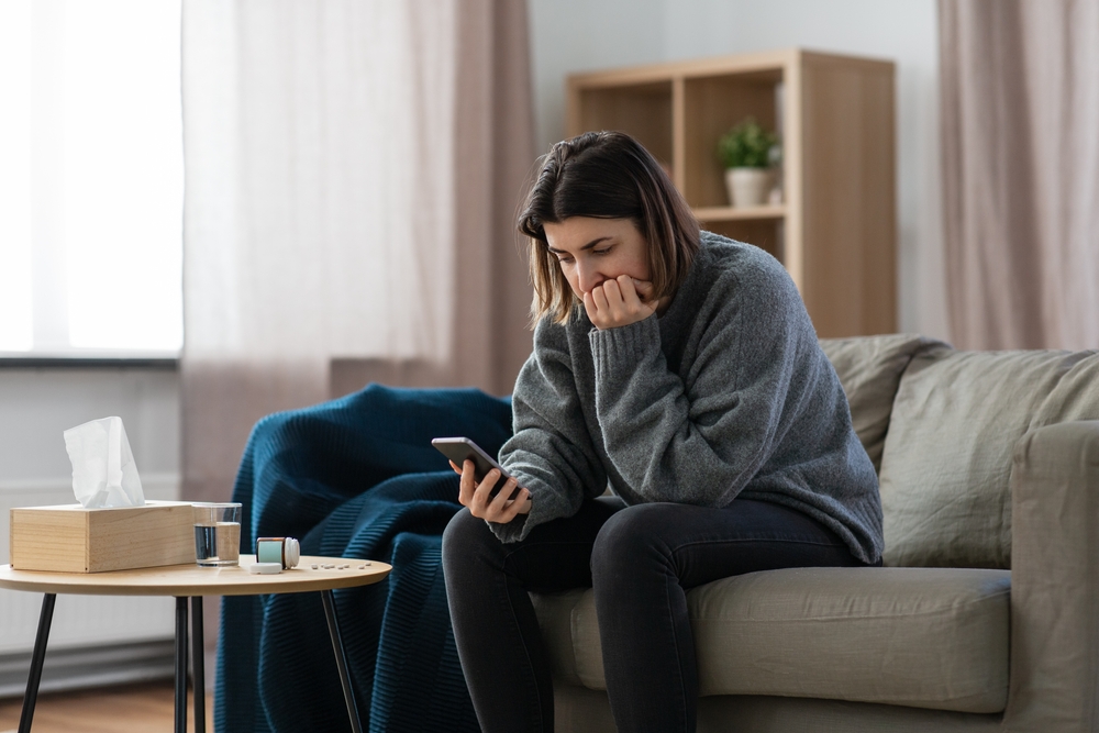 woman sitting on couch looking at phone