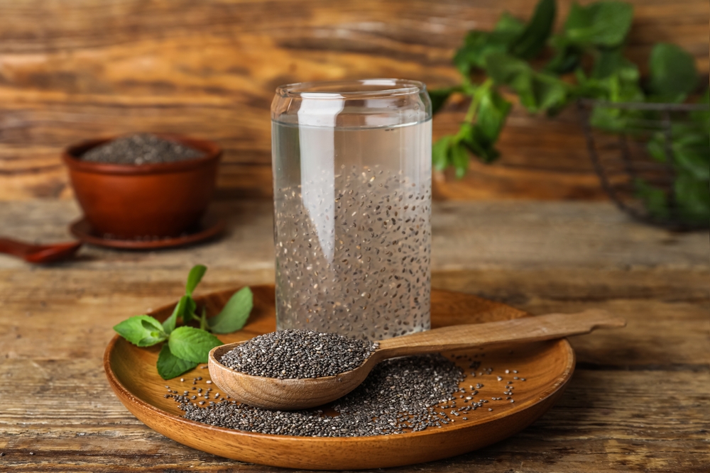 Glass with drink and chia seeds on wooden background