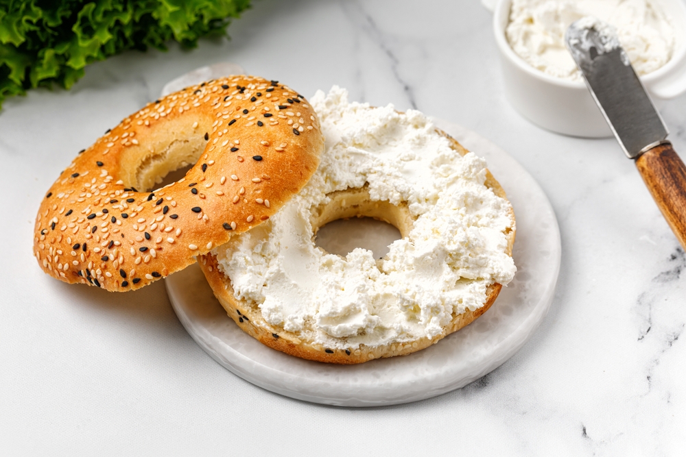 Baked Bagel sandwich with cream cheese on marble board and white background
