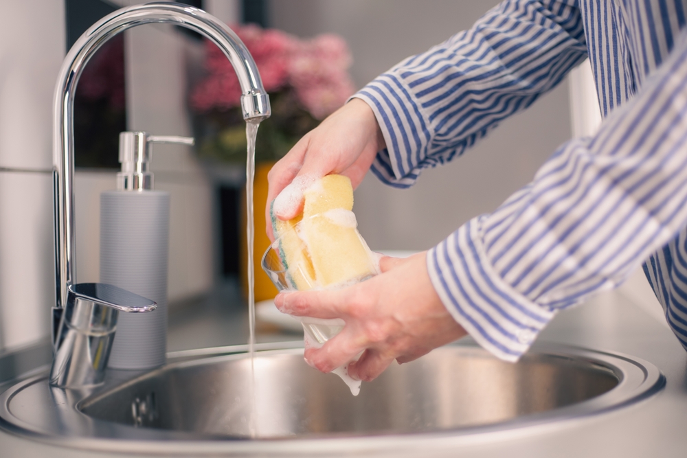 Close up of woman housewife is doing the dishes at home kitchen by using wash sponge and dishwashing.