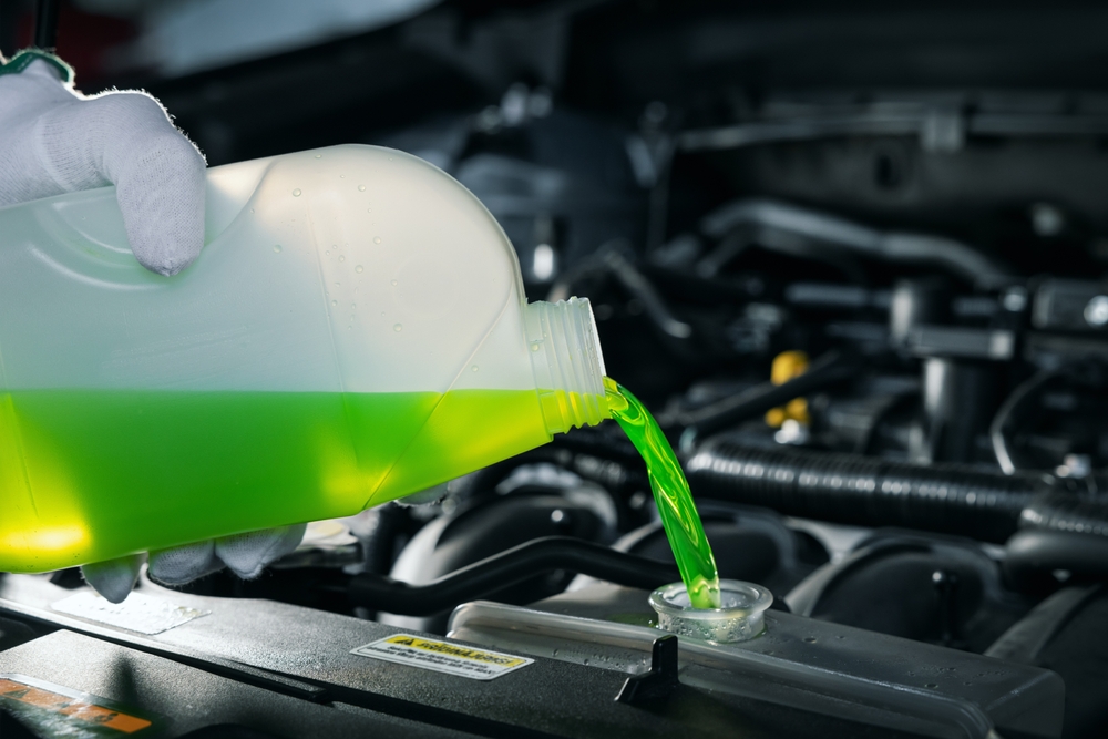 pouring antifreeze coolant liquid into car engine radiator