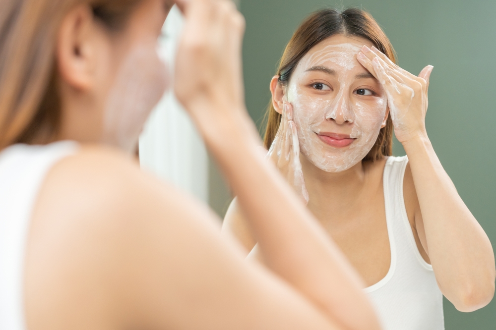 Cheerful asian young woman, beauty girl hand applying foam cleanser for washing on her face, clean fresh healthy skin care, exfoliation scrub soap with cleansing product. Skincare spa relax concept.
