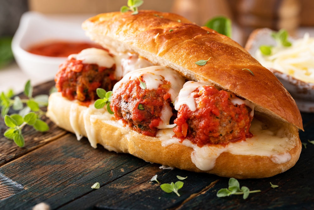 Meatball sub sandwich with marinara and mozzarella and fresh herbs