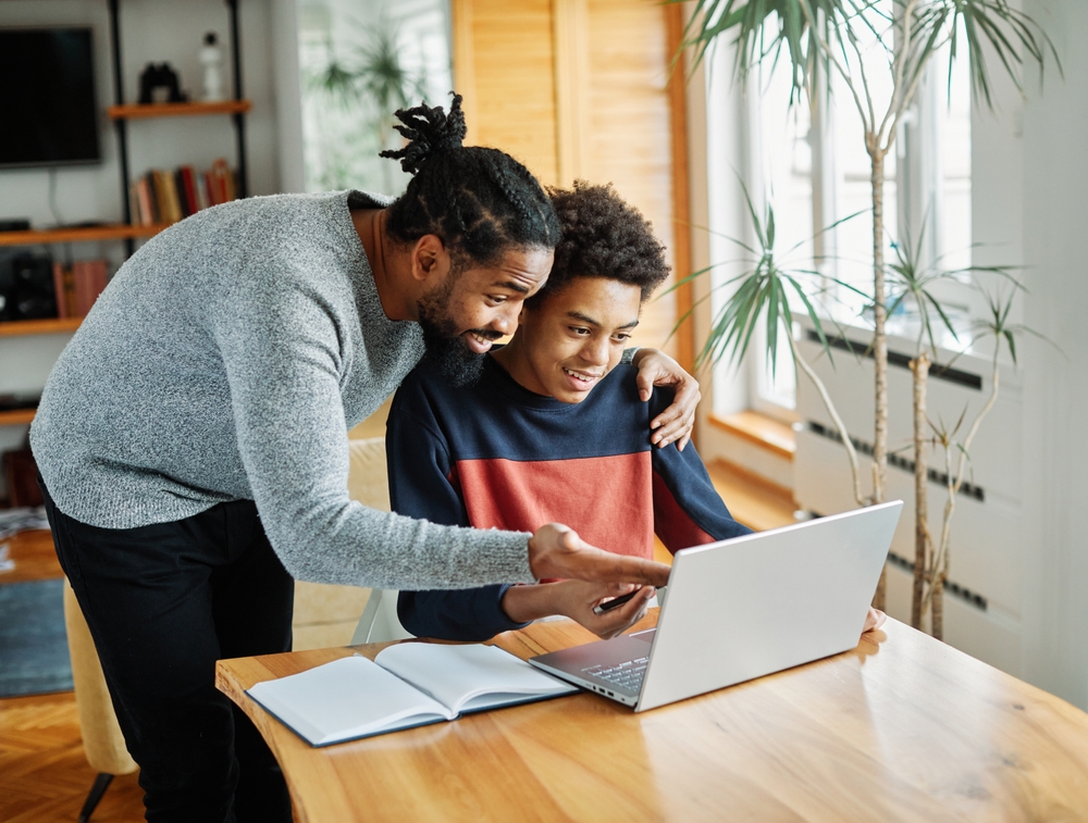 father helping son on laptop