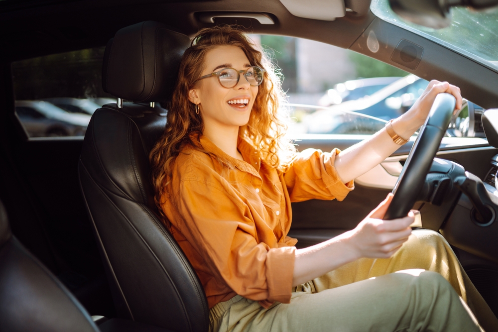 Smiling woman driving a car. Young traveler driving. Car travel, lifestyle concept.
