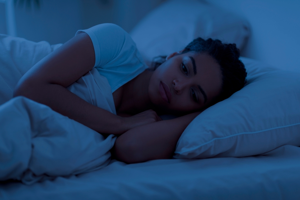 Awake sleepless upset black woman lying in bed alone at night, cant sleep, feeling lonely, suffering from depression or anxiety, experiencing difficulties with sleeping, resting in home interior