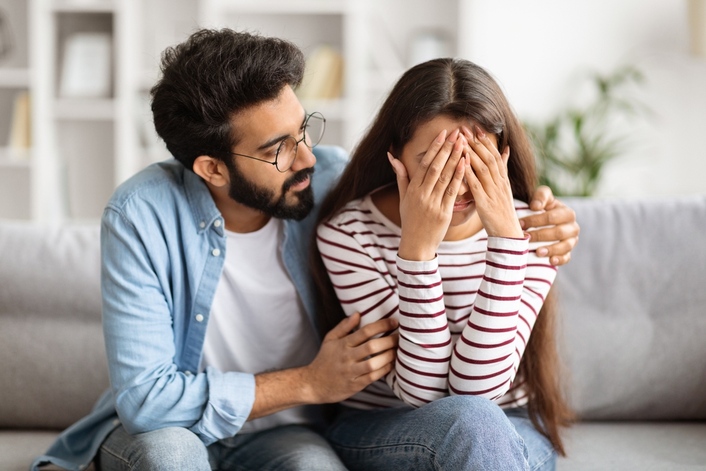Loving husband indian man comforting consoling upset crying wife woman, giving psychological support care compassion, helping sharing grief or problem, miscarriage, empathy in couple relationships
