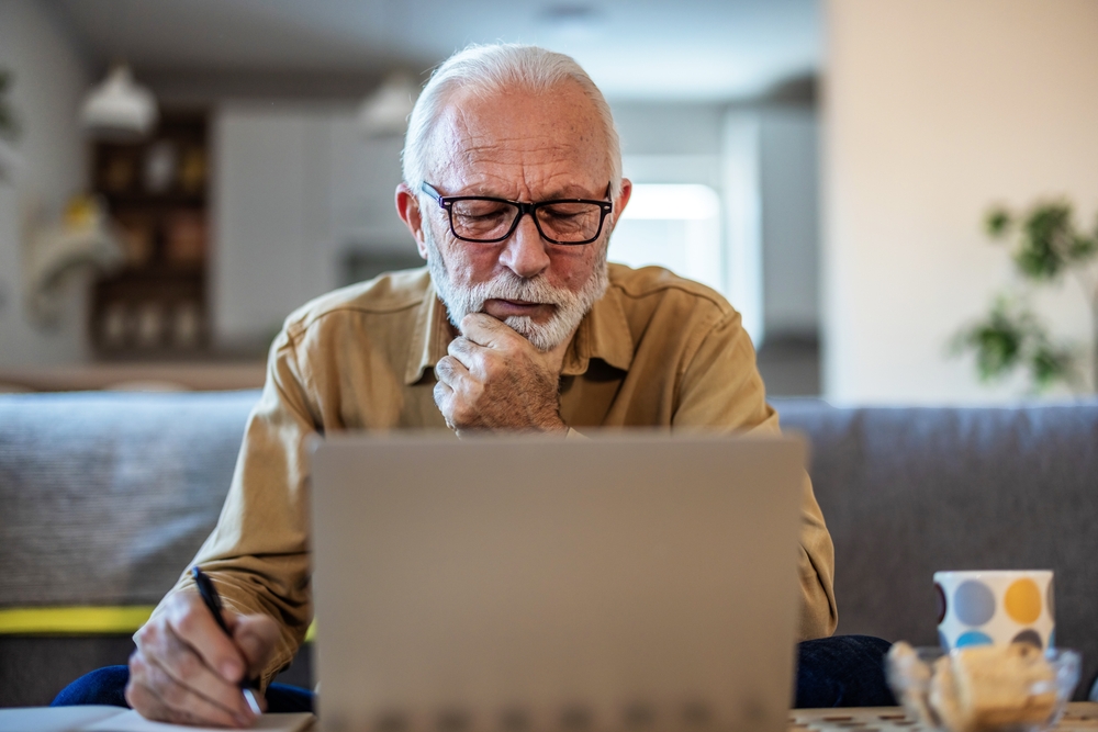 Finance, retirement and old man with paperwork, laptop and budget plan, checking investment and taxes. Mortgage, insurance document and online pension savings review, senior man with debt in home.