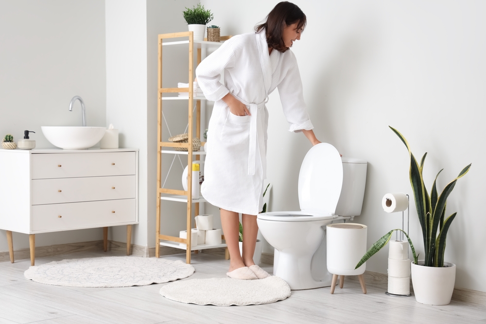 Young woman flushing toilet in restroom