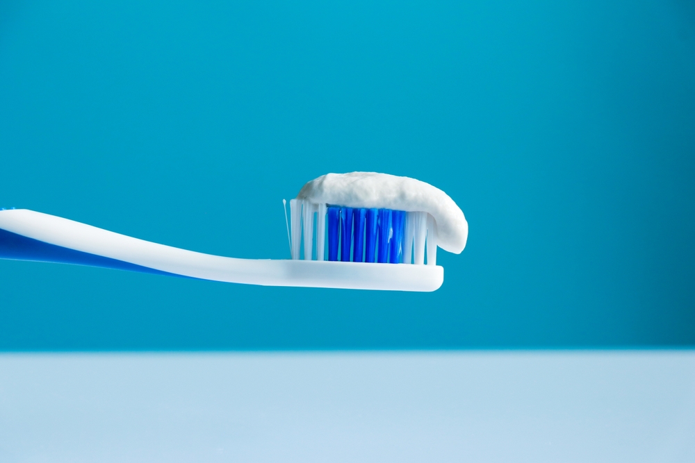 Toothpaste on a toothbrush close-up on a cyan-white background

