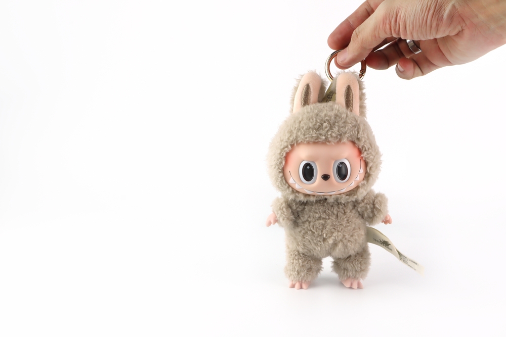 art toys Labubu key chain collection from Pop Mart blind box collectable cute toys is held by right hand on white shelf at Pop mart store during new release promotion event labubu macaron cute doll