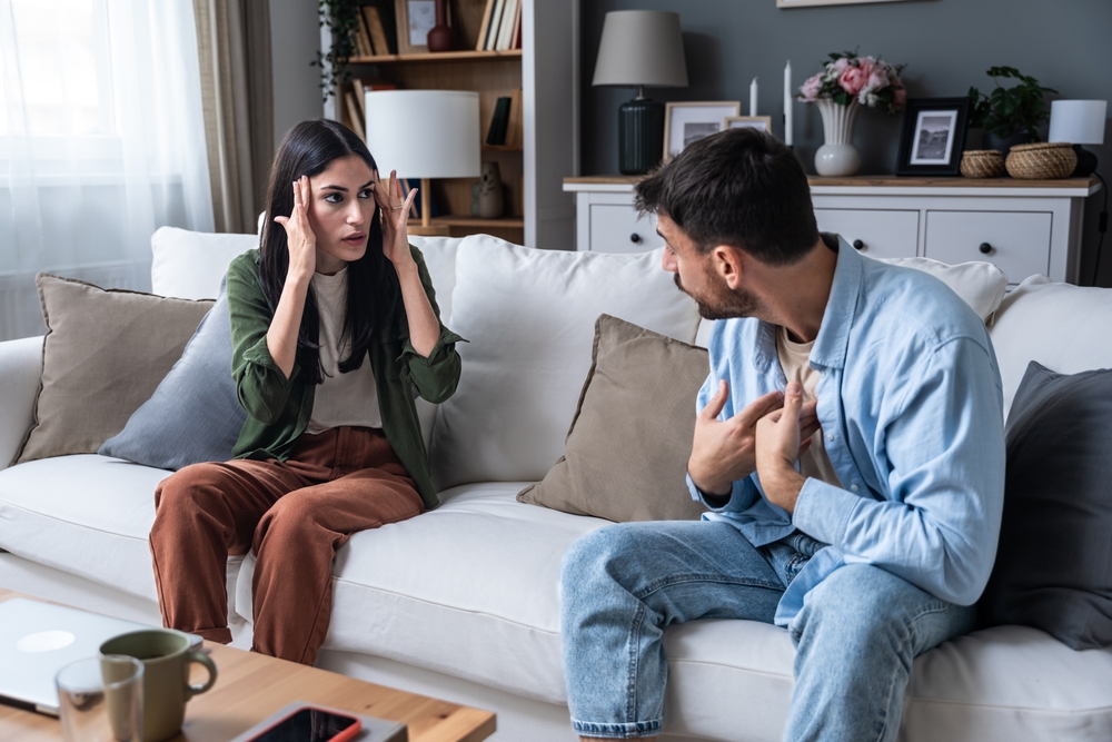 Young married couple husband and wife sitting at home having problems in their marriage and a cold relationship. A boyfriend and a girlfriend roommates have an argument about spending too much money
