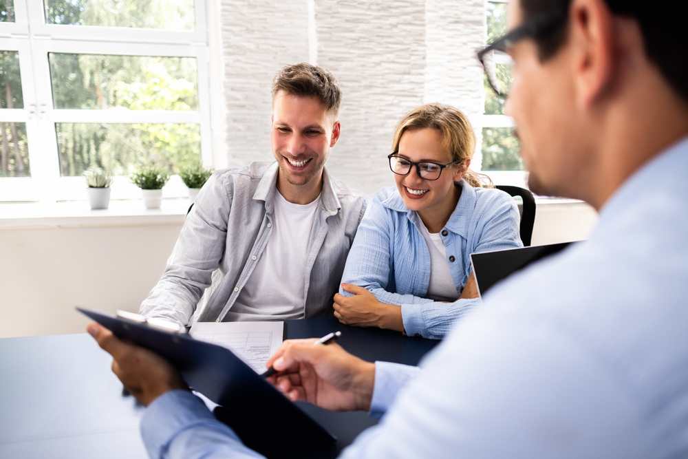 Financial consultant explaining new project investment to young couple in office. Real estate agent discussing mortgage options with family. Mortgage loan consultation with financial advisor.