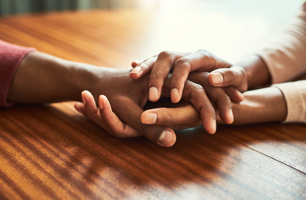 Couple, holding hands and above for empathy in home for care, connection and motivation for mental health. People, comfort and partner for help with kindness, bonding and support for grief on table
