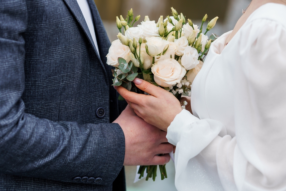 Elegant Wedding Couple Holding a Beautiful Bouquet of White and Green Flowers.
