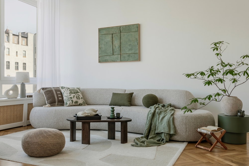 A modern, minimalist interior with a large sofa and natural accents. Soft greens bring harmony to the space, creating an elegant, calming atmosphere.