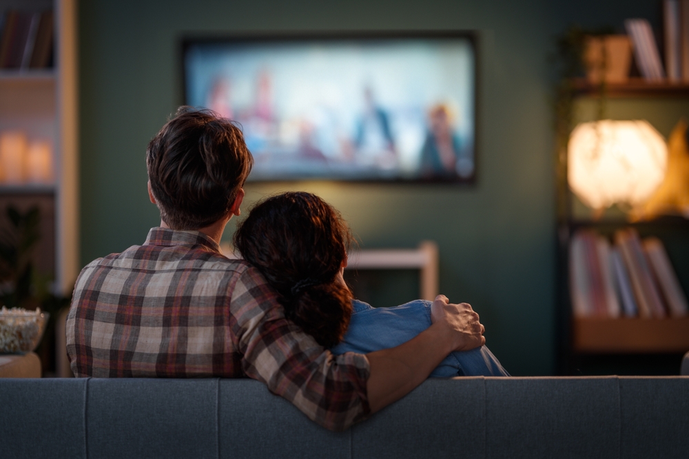 Happy family watching TV, movies in the evening at home. Couple spending time together.