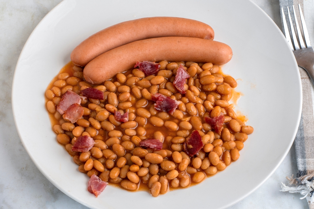 two natrual casing hot dogs served with baked beans top with bacon bits, 