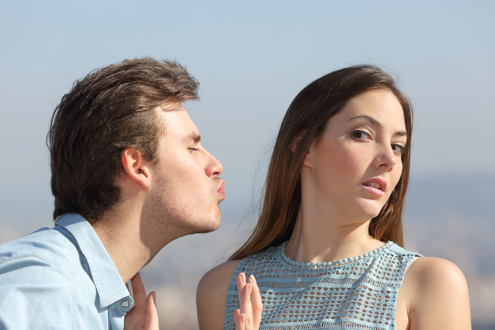 Friend zone concept with a man trying to kiss a woman and she rejecting him
