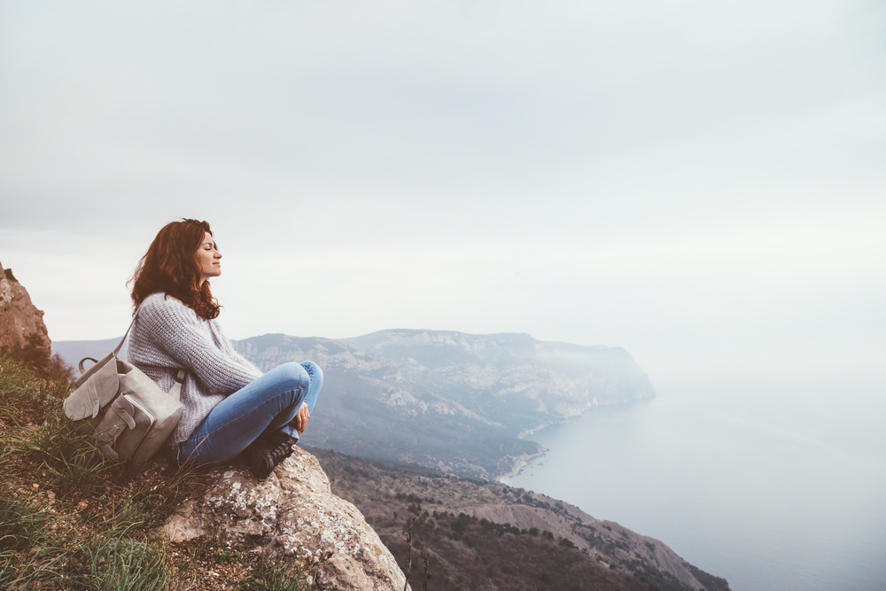 Girl travel in mountains alone. Spring weather, calm scene. Backpacker walking outdoors, back view over landscape. Wanderlust photo series.
