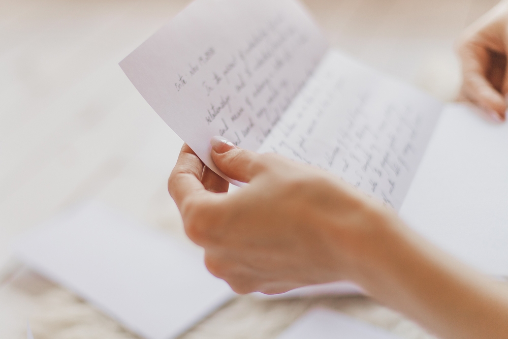 Hands of young woman holding handwritten letter
