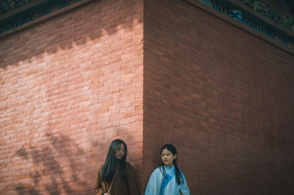 two women holding hands near wall
