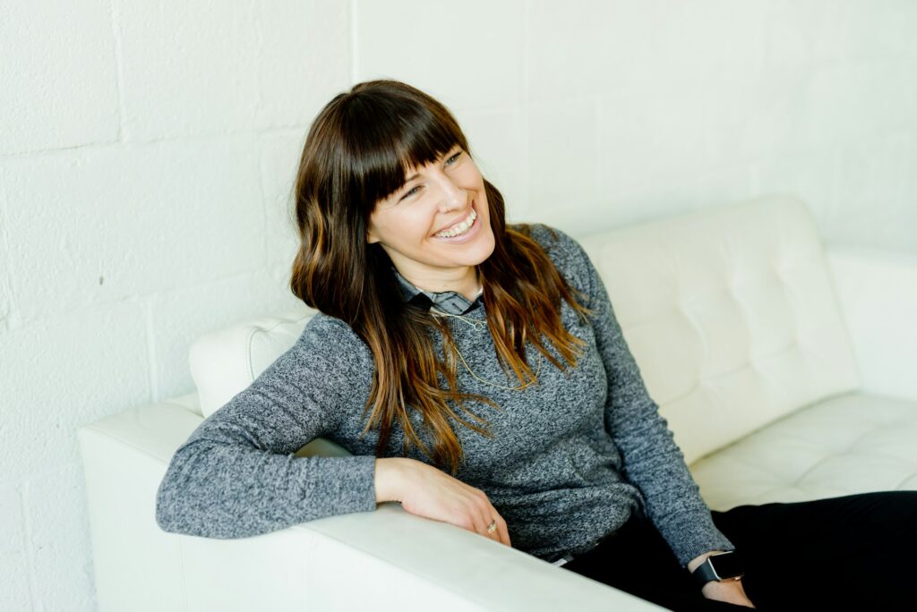 woman in gray sweater sitting on white chair
