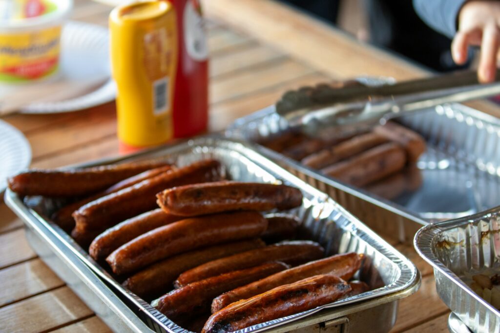 A couple of pans filled with hot dogs on top of a wooden table
