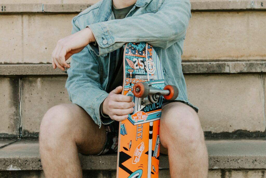 man wearing demin jacket holding a  skateboard
