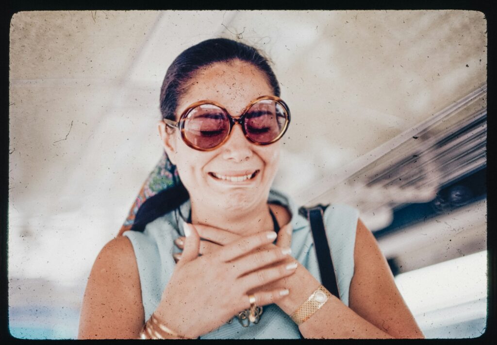 A woman wearing sunglasses is smiling for the camera
