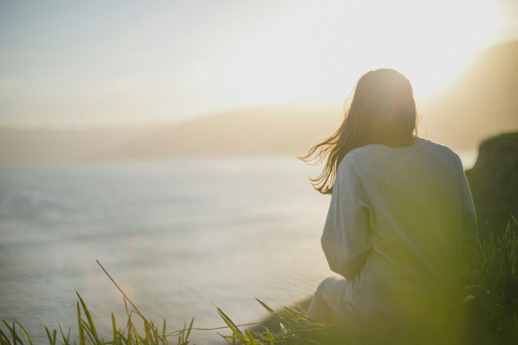 woman wearing gray long-sleeved shirt facing the sea
