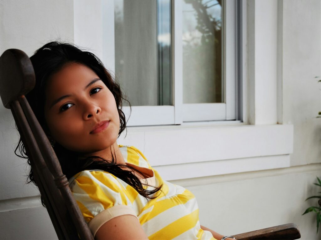 girl in yellow and white stripe shirt sitting on chair
