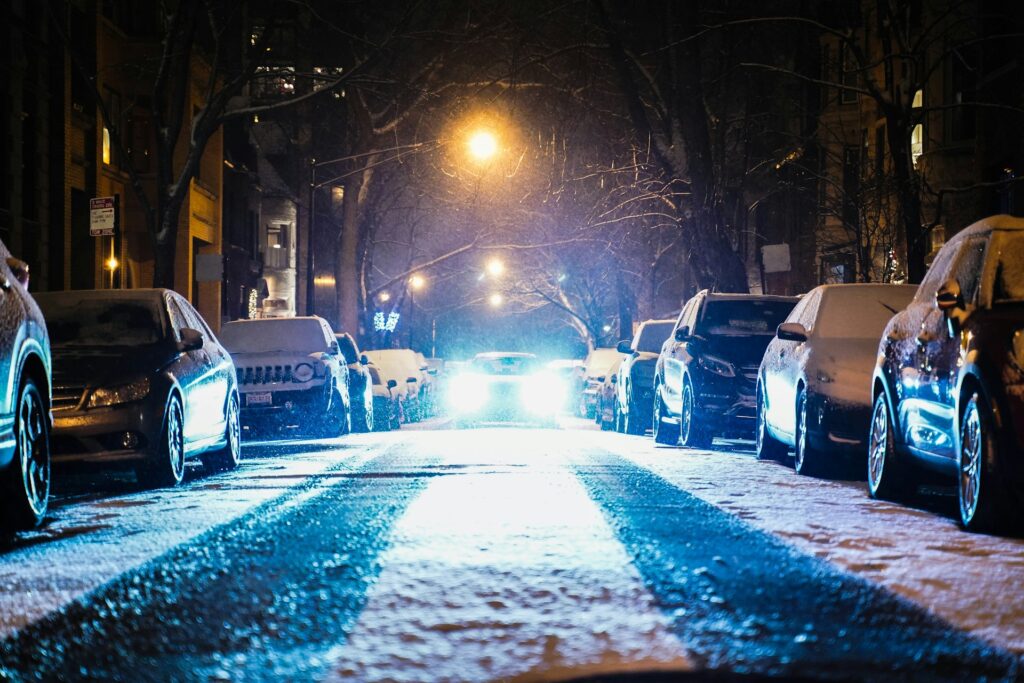 cars parked on both sides of the street during snowy nighttime
