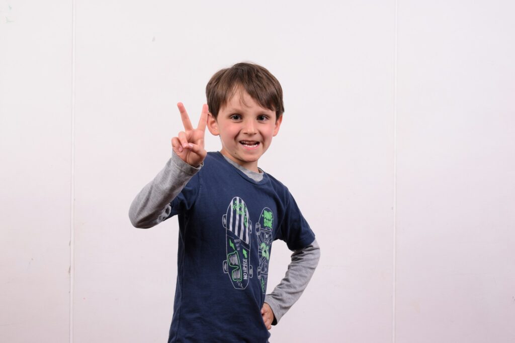 a young boy making a peace sign with his fingers