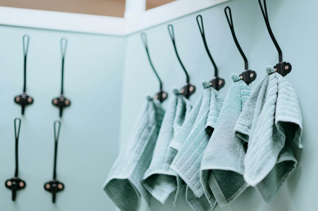 clothes hangers, specifically wall-mounted hooks, with some holding folded towels. 