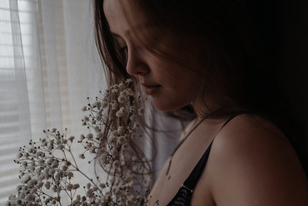 a woman holding a bouquet of flowers next to a window

