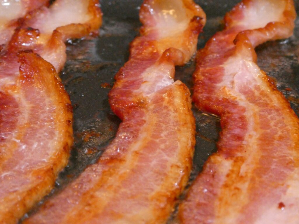 bacon is being cooked in a frying pan
