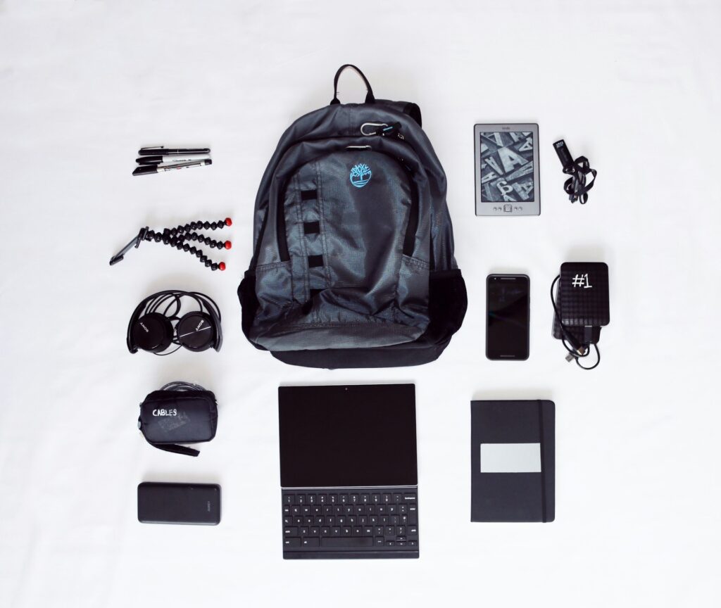 flat lay photography of backpack, laptop computer, headphones, smartphone, and octopus tripod
